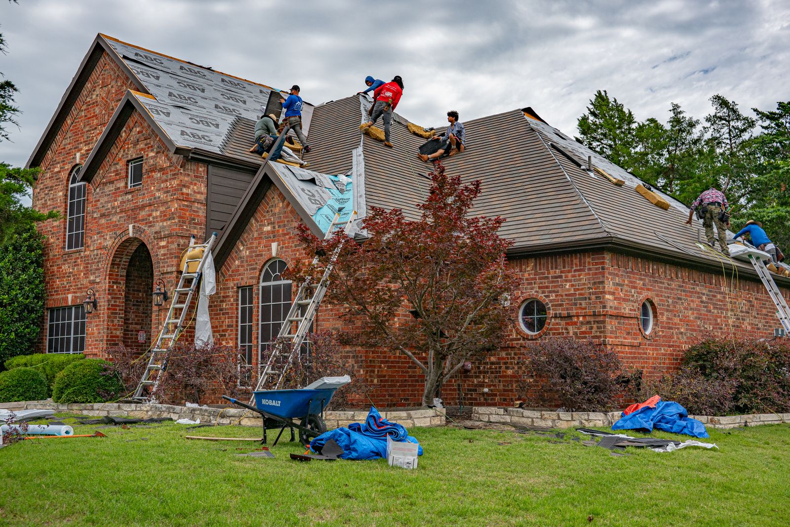Workers renovating the roof of a brick house in Texas